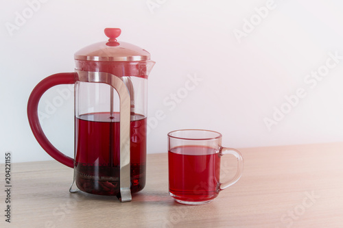 Hibiscus tea in a tea pot. Karkade tea or red sorrel tea in glass pot and cup on white background with copy space.