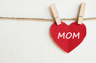 Happy mother's day greeting card, Love mom word on red fabric heart shape hanging over white background with copy space for text