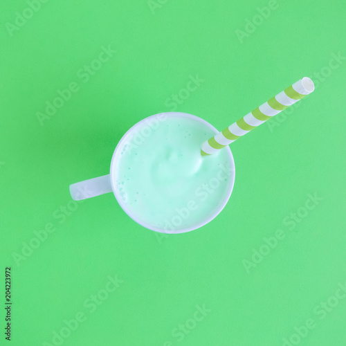 High angle view of cup of fruit smoothie on green background.