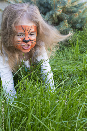Close-up emotional portrait of a little girl with tiger aqua makeup. baby growls like a tiger