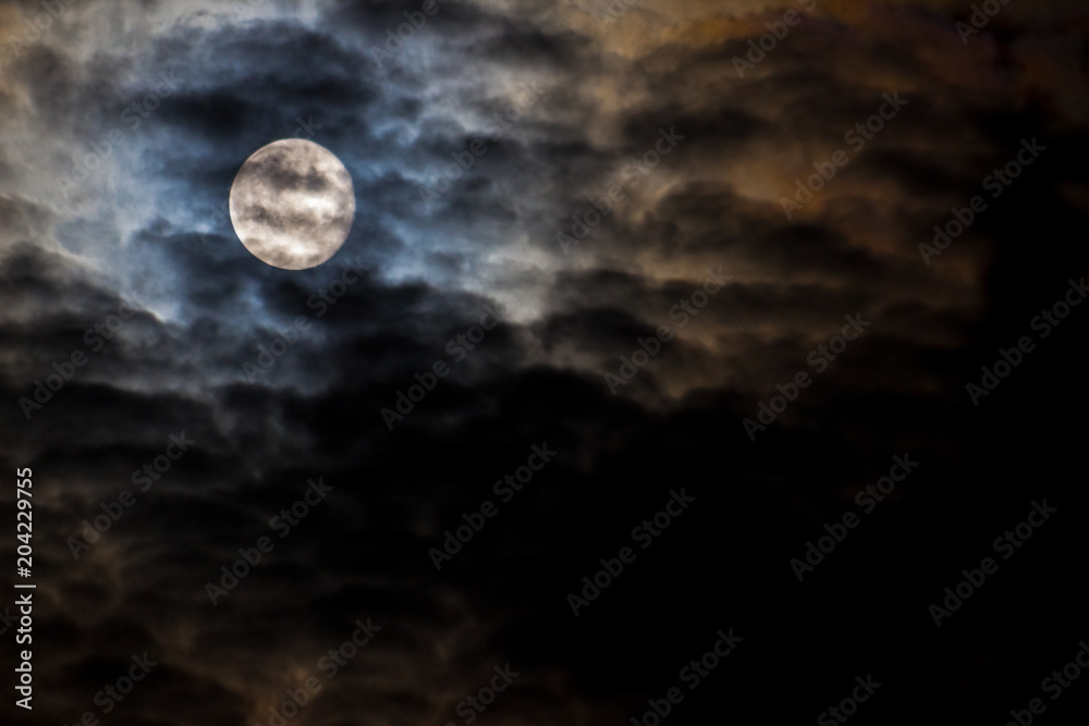 The moon behind the dark clouds