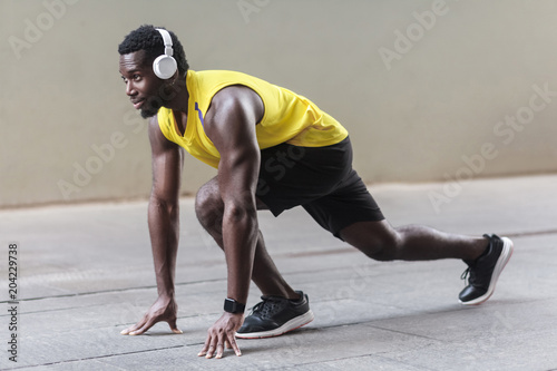 Profile view. African athlete man in running start pose