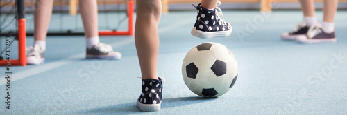 Billede på lærred Kid in sneakers playing football