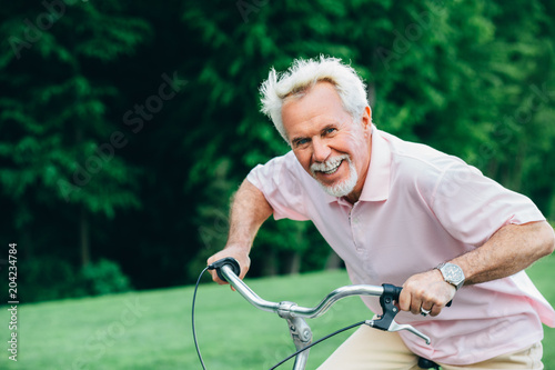 lively older man riding his bicycle, laughs and enjoys life. Senior man on bike, having fun © Peakstock