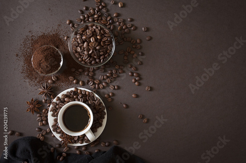 Сoffee in white cup, сoffee beans and ground powder on brown background