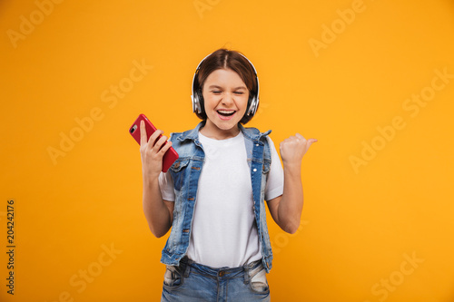 Portrait of an excited little schoolgirl listening to music