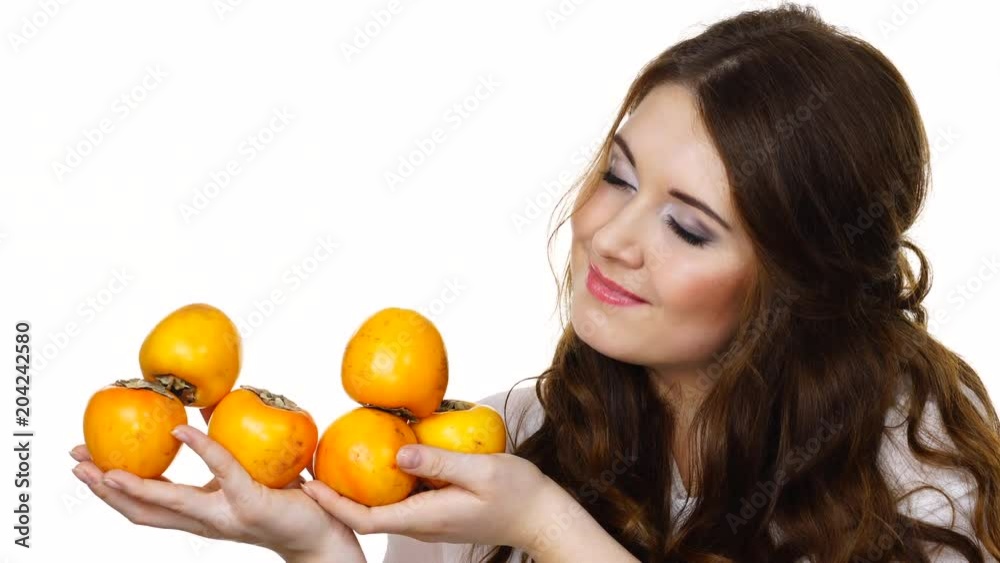 Woman smiling brunette girl holding many persimmon kaki fruits in hands, isolated on white. Healthy eating, vegetarian food, diet concept. Woman smiling brunette girl holding many persimmon kaki fruits in hands, isolated on white. Healthy eating, vegetarian food, diet concept.