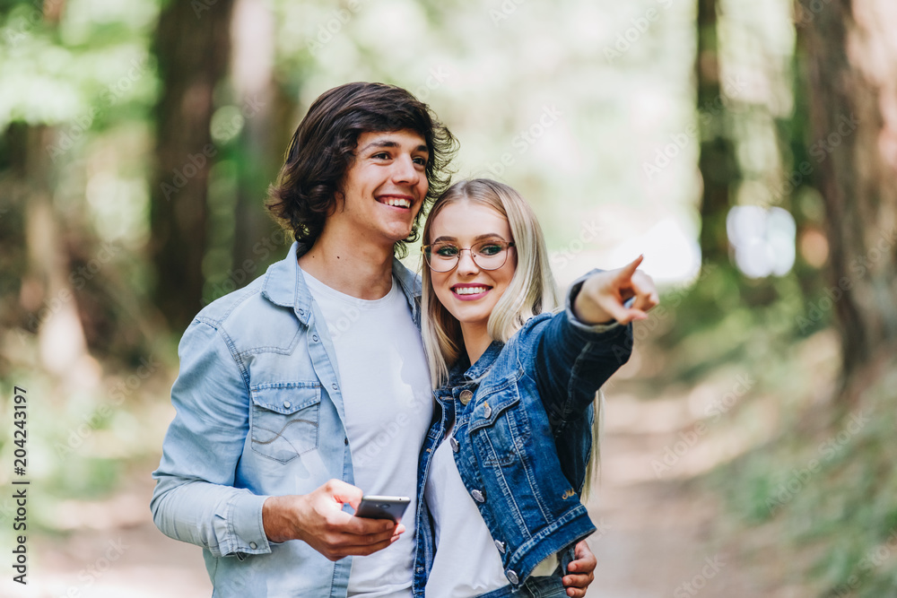 Fototapeta premium Young couple on adventure in forest using GPS on smartphone as orientation