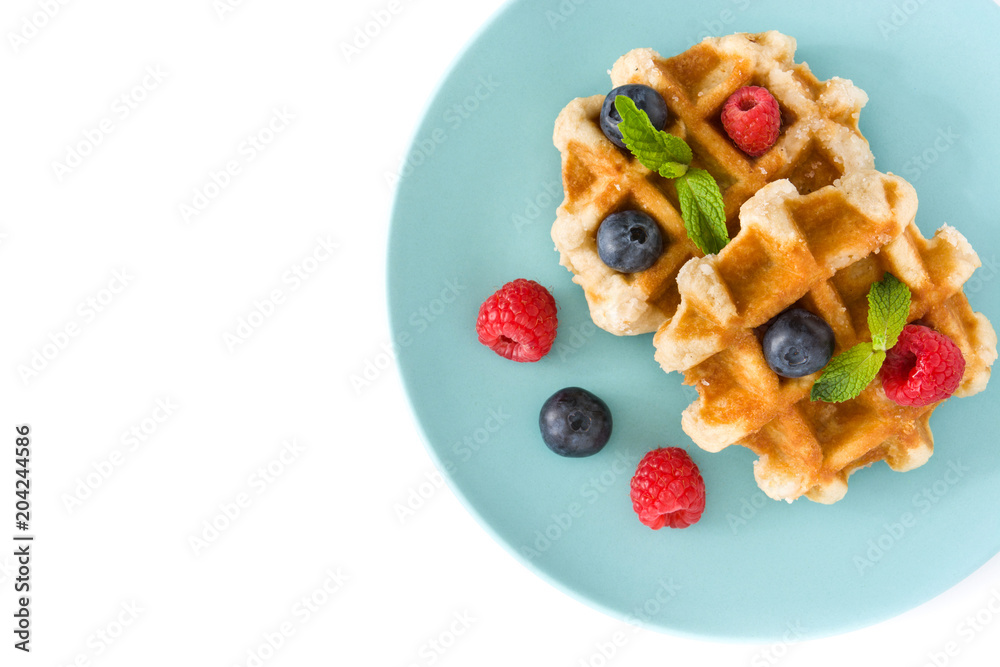 Traditional belgian waffles with blueberries and raspberries, isolated on white background. Top view. Copyspace
