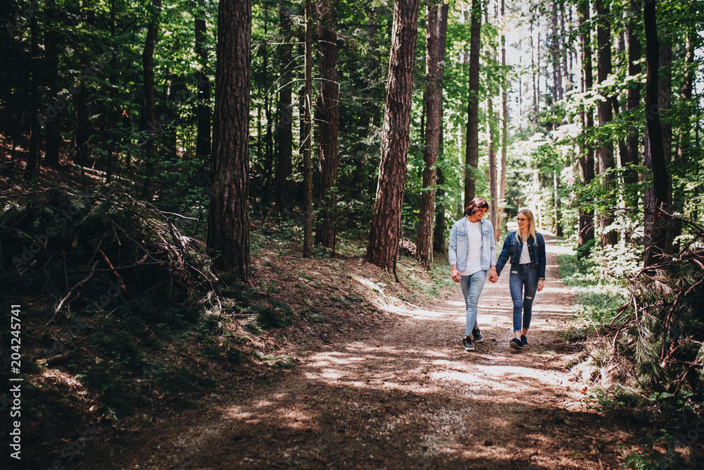 Young couple walking, hand in hand, through forest