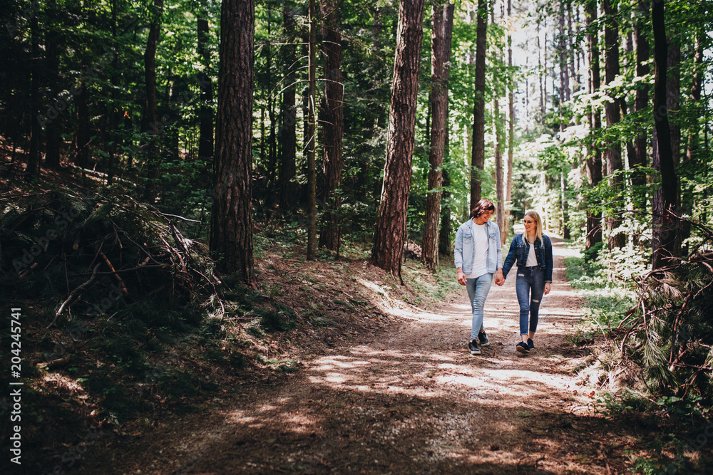 Young couple walking, hand in hand, through forest Young couple walking, hand in hand, through forest