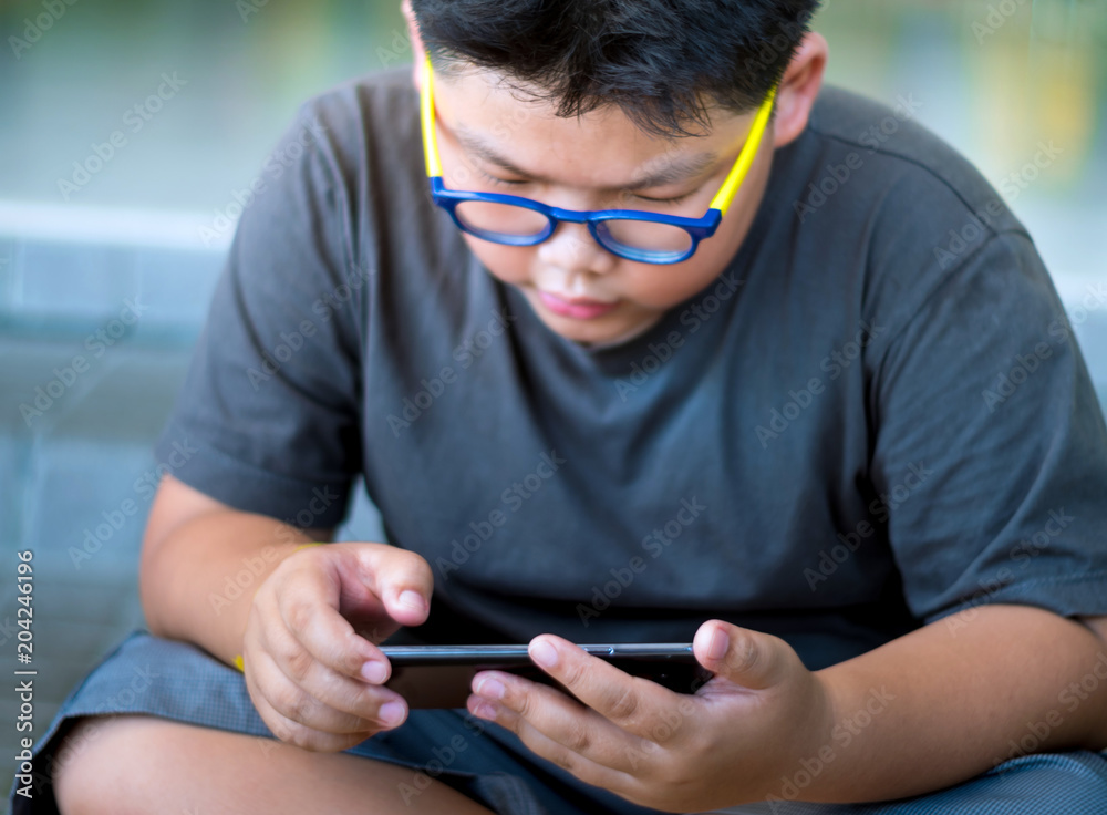 Asian boy have a serious face while playing game on smartphone Asian boy have a serious face while playing game on smartphone