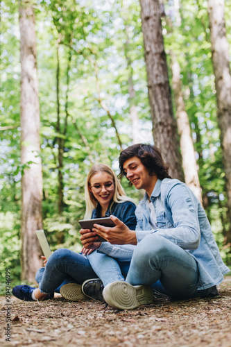 Young couple using tablet while sitting in forest