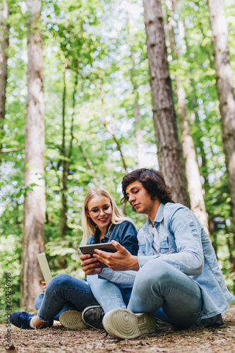 Young couple using tablet while sitting in forest
