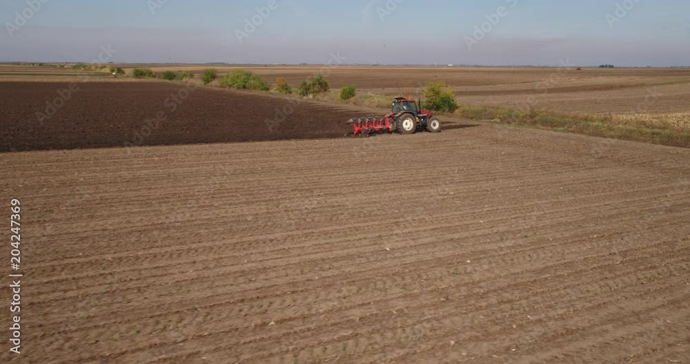 Aerial shot of a farmer plowing stubble field Aerial shot of a farmer plowing stubble field