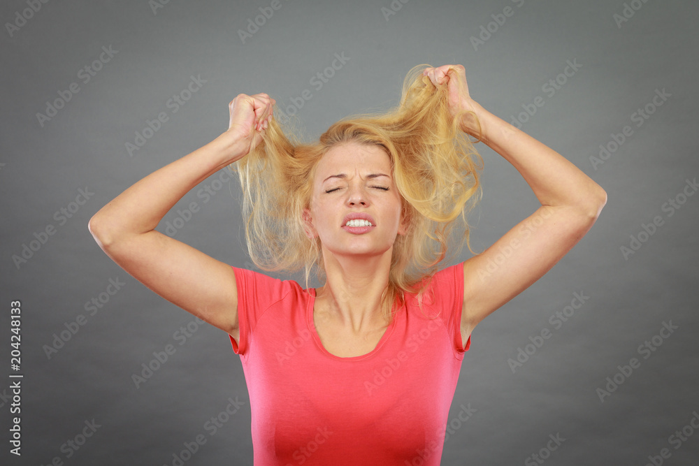 Frustrated woman holding her damaged blonde hair Frustrated woman holding her damaged blonde hair