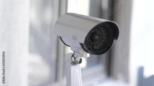 Security camera moving panning and tilting recording what's happening outside a building. Motorized CCTV surveillance.