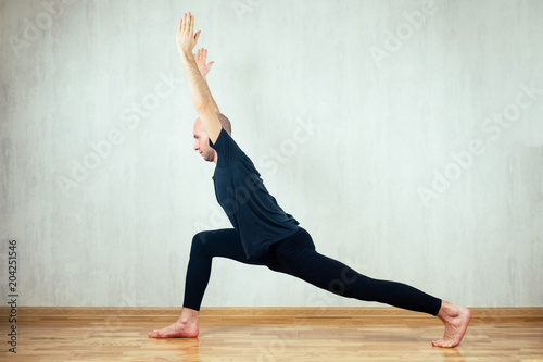 young and athletic man practices yoga and performs asanas in the gym