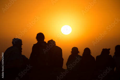 Silhouette einer  Gruppe von jungen Leuten sehen beim Sonnenuntergang zu 