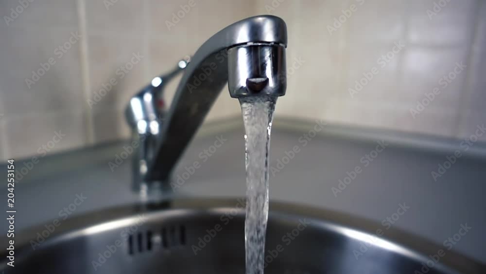 Tap water flows from tap in kitchen in slow motion. City life modern human. Videography of home life. Tap water flows from tap in kitchen in slow motion. City life modern human. Videography of home life.