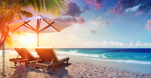 Slika na platnu Two Deckchairs Under Parasol In Tropical Beach At Sunset