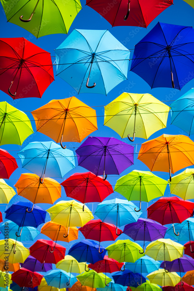 Colorful umbrellas background. Coloruful umbrellas urban street decoration. Hanging Multicoloured umbrellas over blue sky. umbrellas with many colours.