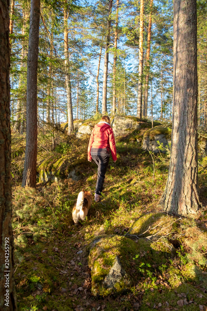 A woman and dog hiking in finnish forest