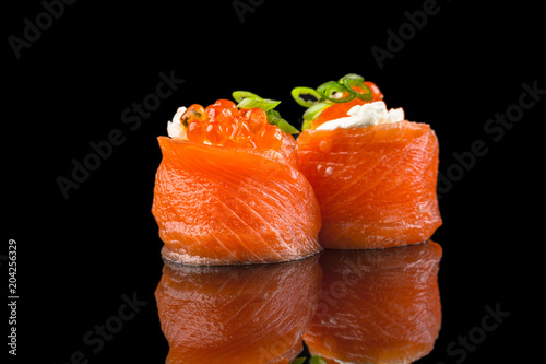 fresh salmon sushi with egg yolk and caviar on the black background