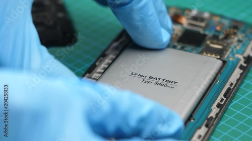Replacing the internal battery of a smartphone mobile device. Closeup of the repair being done by a person wearing gloves.