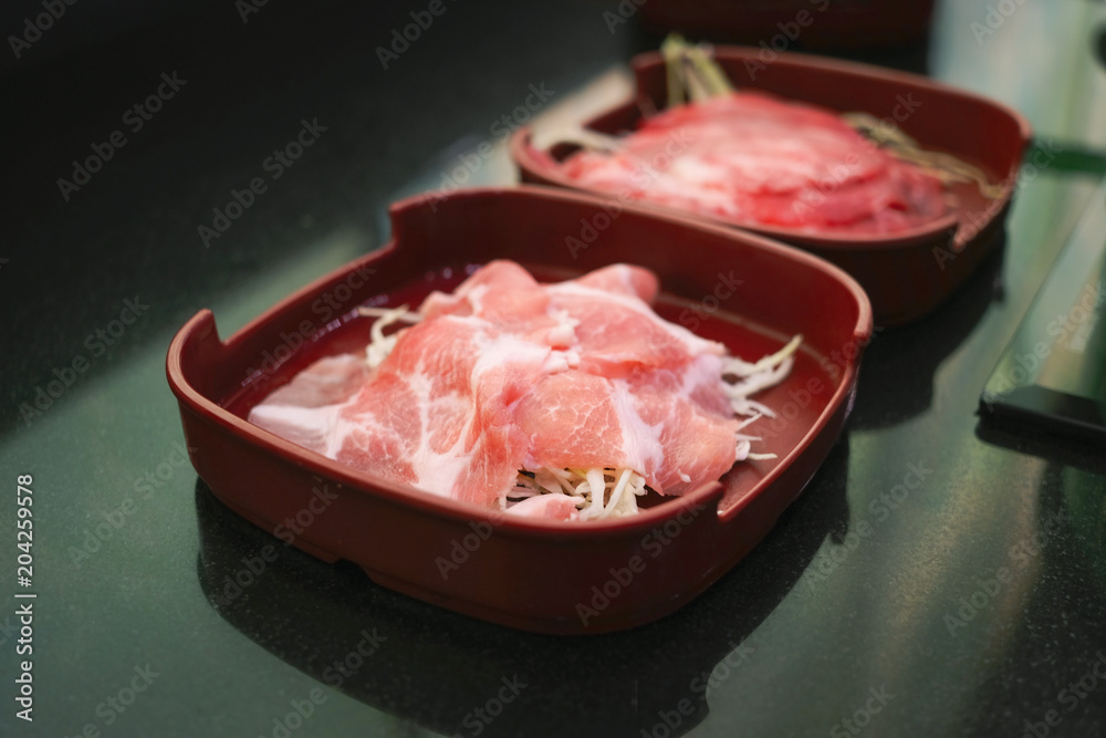 Raw fillet pork and beef sliced on red dish Raw fillet pork and beef sliced on red dish