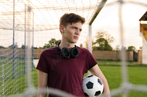 Beautiful teenager holding soccer ball , footballer , soccer player, standing in goal 