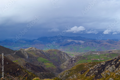 Far view of a field from the top of a mountain. Green field in a cloudy sky