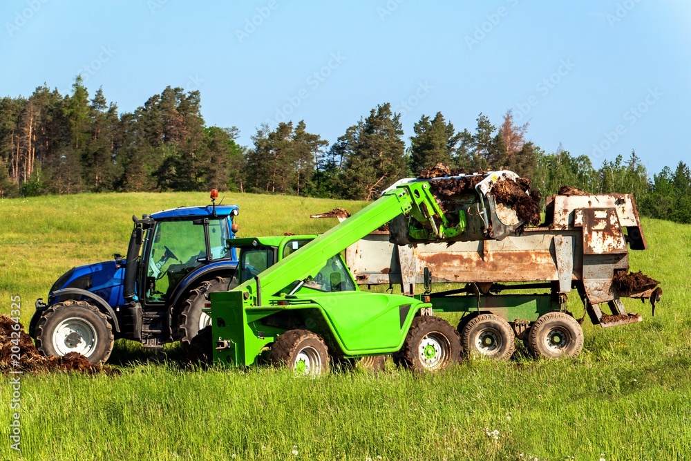 Natural manure agro bio fertilization. Loading manure onto tractor. Agricultural landscape in the Czech Republic. Natural manure agro bio fertilization. Loading manure onto tractor. Agricultural landscape in the Czech Republic.