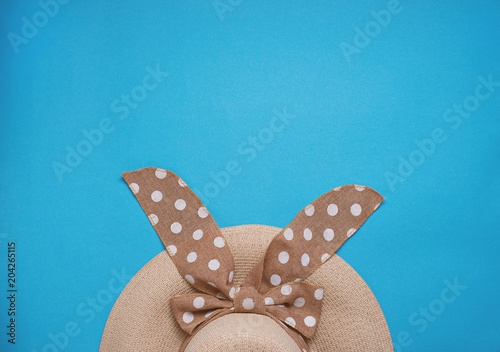 Straw womans hat with ribbon on blue background.