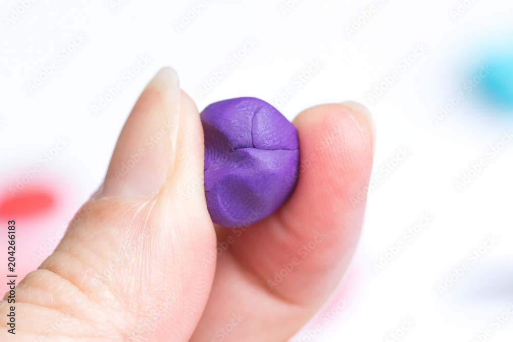 A purple ball of plasticine in the woman's hand. A purple ball of plasticine in the woman's hand.