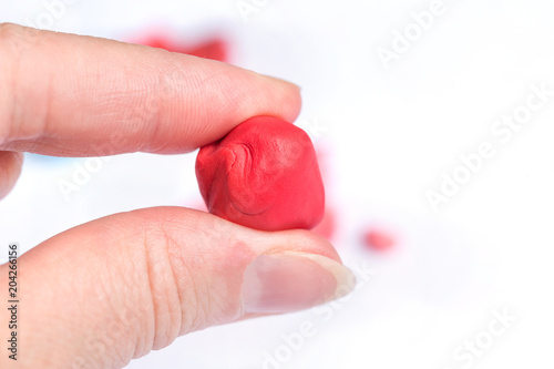 A red ball of plasticine in the woman's hand.