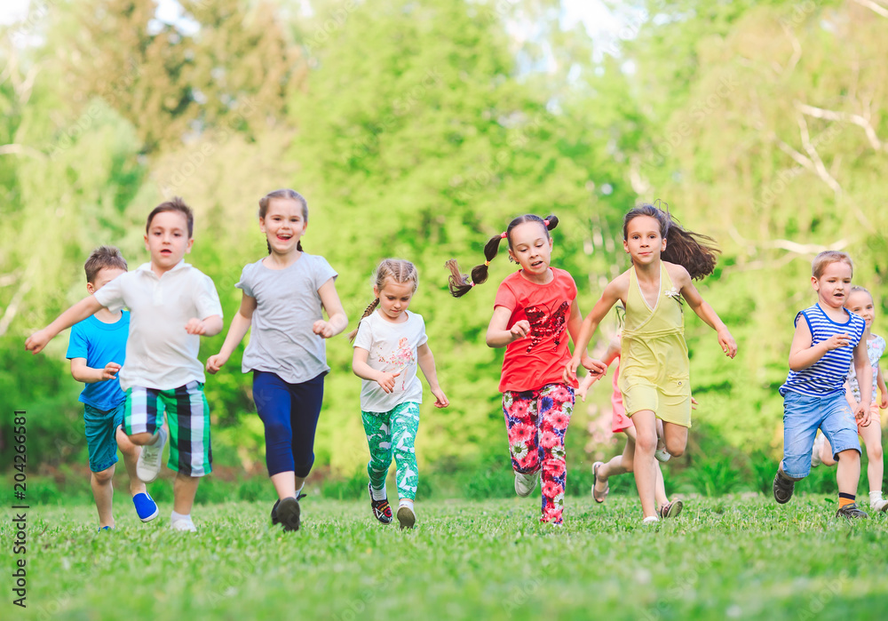 Many different kids, boys and girls running in the park on sunny summer day in casual clothes