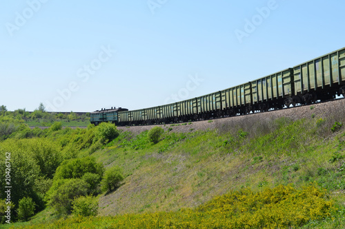 Freight train moving among forests and meadows