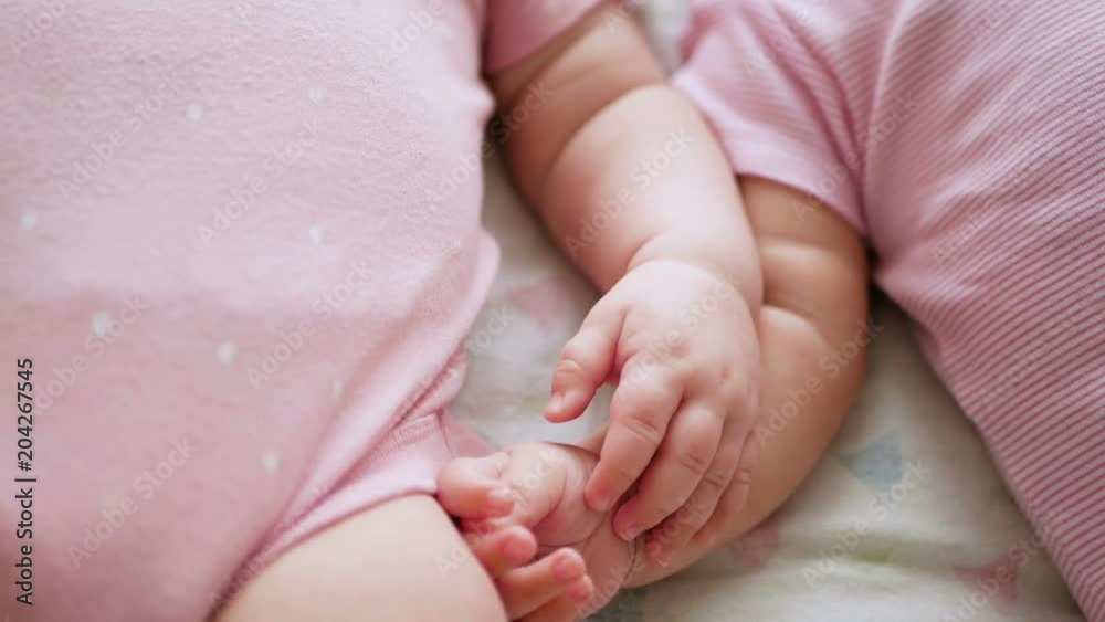 two girls twins hold hands while lying in bed two girls twins hold hands while lying in bed