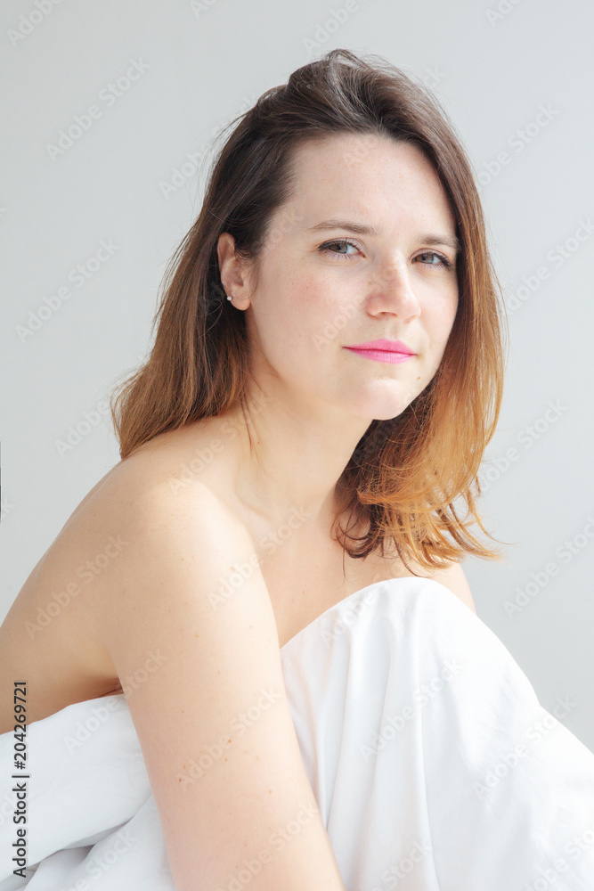 brunette young woman sitting in bed with white bedsheets brunette young woman sitting in bed with white bedsheets