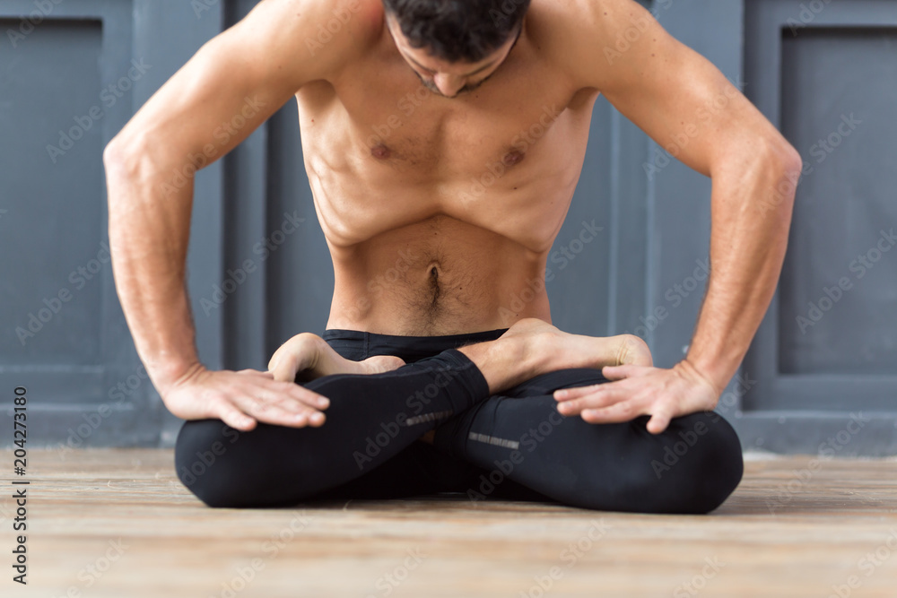 Obraz premium Yoga concept. Portrait of yogi men doing abs exercise, he breath and practicing Upward abdominal lock, Uddiyana Bandha, vacuum. Young sporty men workout in urban studio.