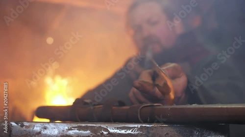 The medieval blacksmith taken sword to examine metal of sword photo