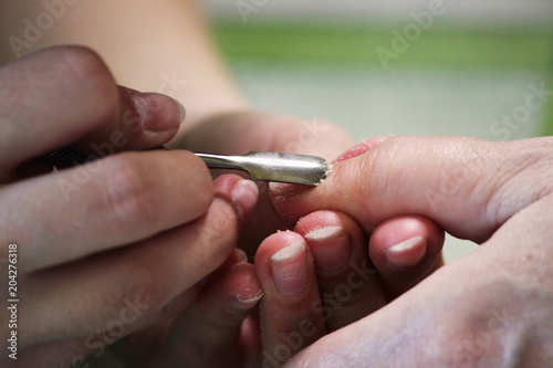 A student at the training courses of a manicure prepares the hand of a lady client with tool for scraping scraper before applying shellac