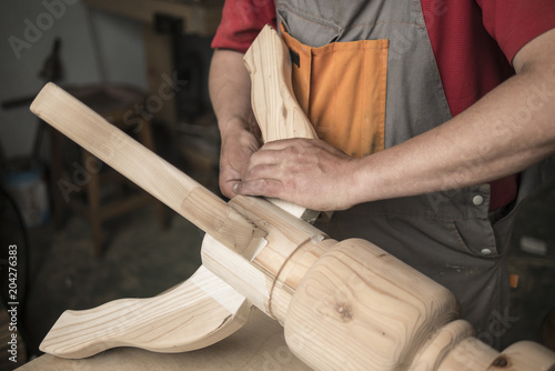 Quadro su tela woodworker, carpenter makes a table with carved legs of pine