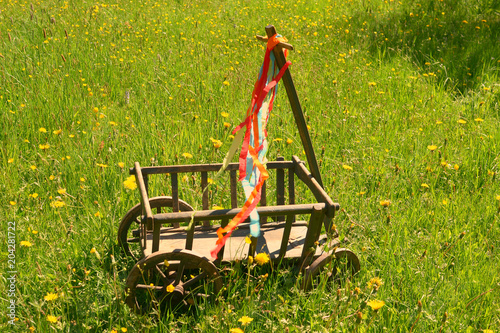 A handcart with a blanket, a beer box, colorful ribbons on a wonderful spring meadow for fathers day