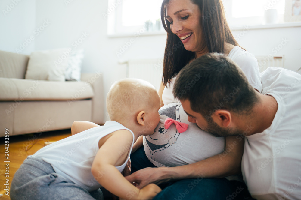 A happy family is having fun with your little child on the floor. Pregnant woman and her husband in the expectation of the birth of a new baby.