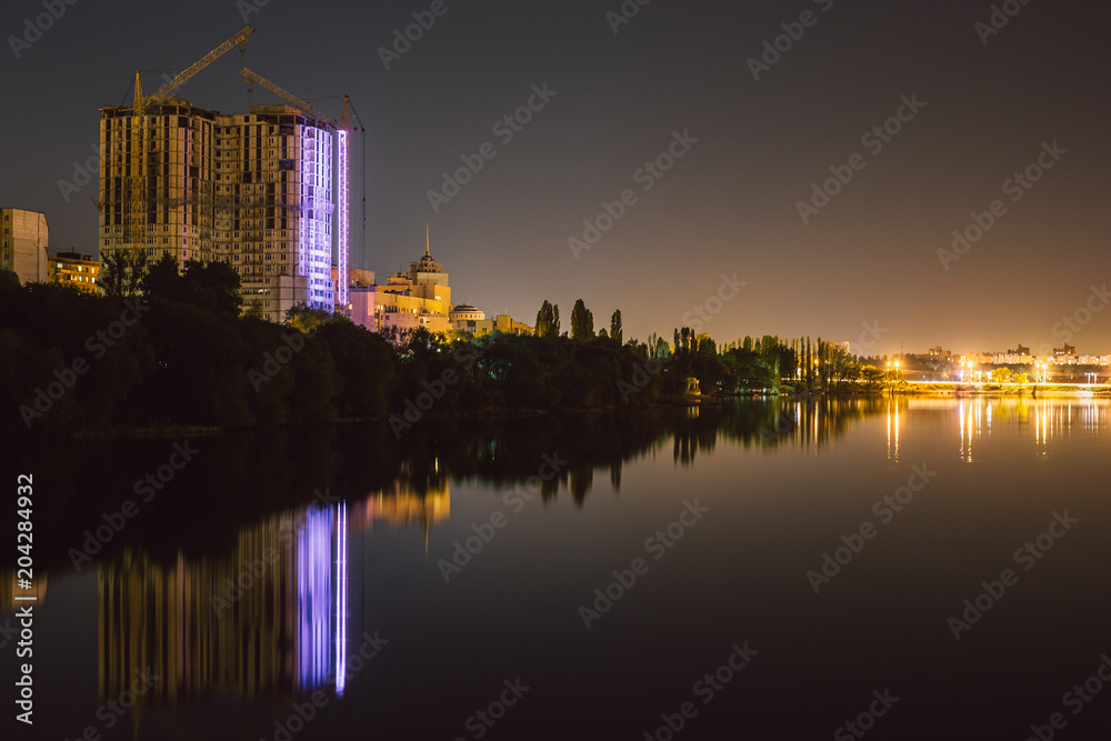 Reflection of large under construction house with illumination in lake water urban night landscape