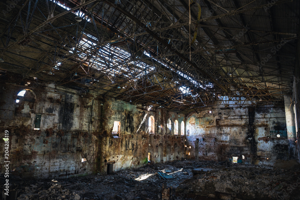 Ruined and abandoned dark creepy factory house building inside, industrial warehouse hall waiting for demolition