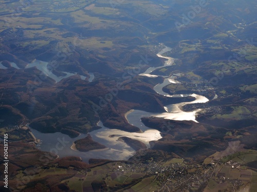 Viewo n a snake-like lake reflecting sunlight from aerial perspective, Germany
