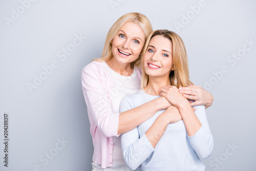 Lovely single grandma hugging adult charming attractive pretty child, family with one parent looking at camera isolated on grey background